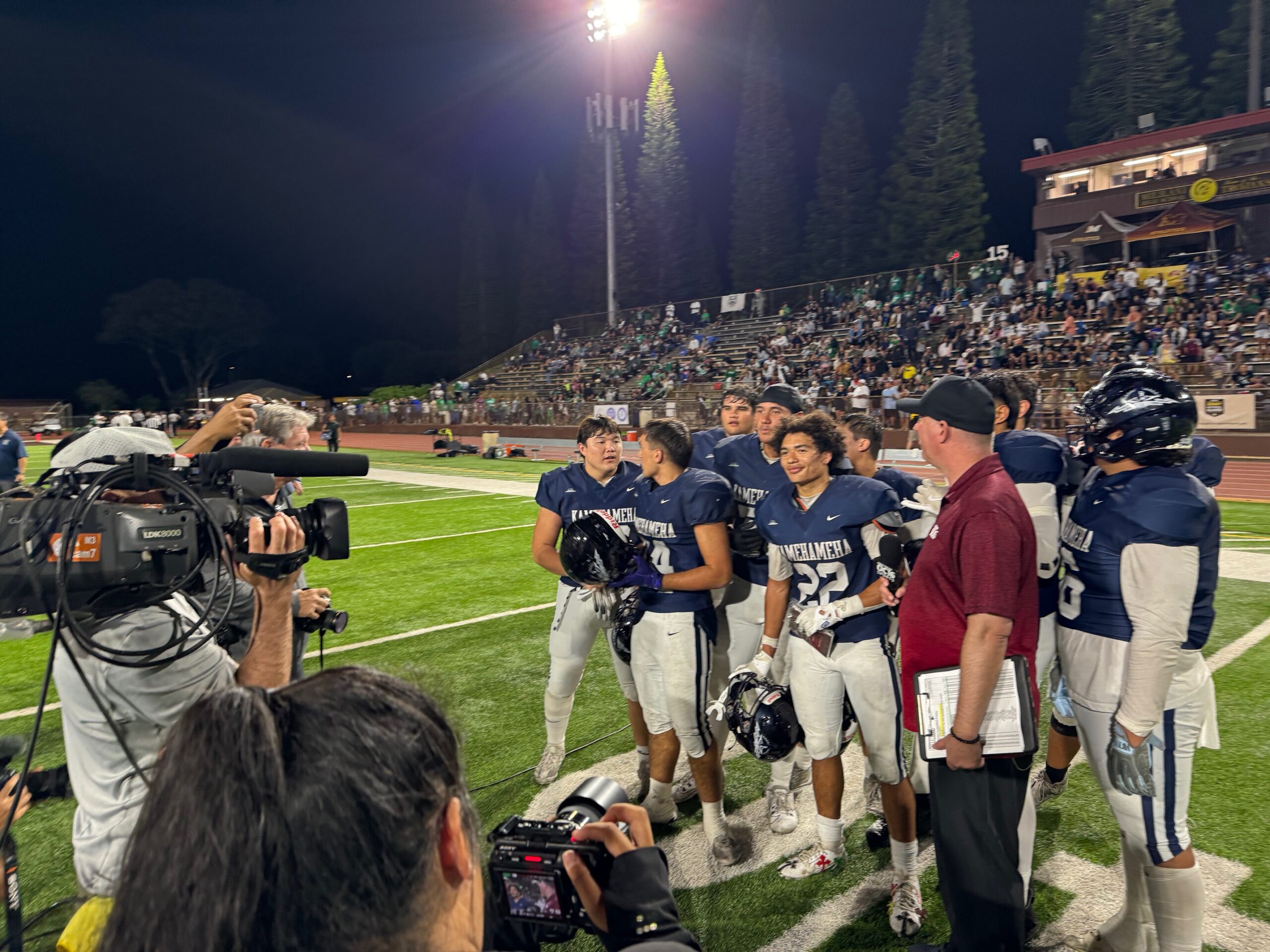 Kamehameha Maui running back Zedekiah Campbell (22) is interviewed by OC-16 television's Jimmy Bender as his Warrior teammates fill in behind. Kamehameha Maui beat Kaiser 37-14 for its first state football championship. HJI / ROB COLLIAS photo