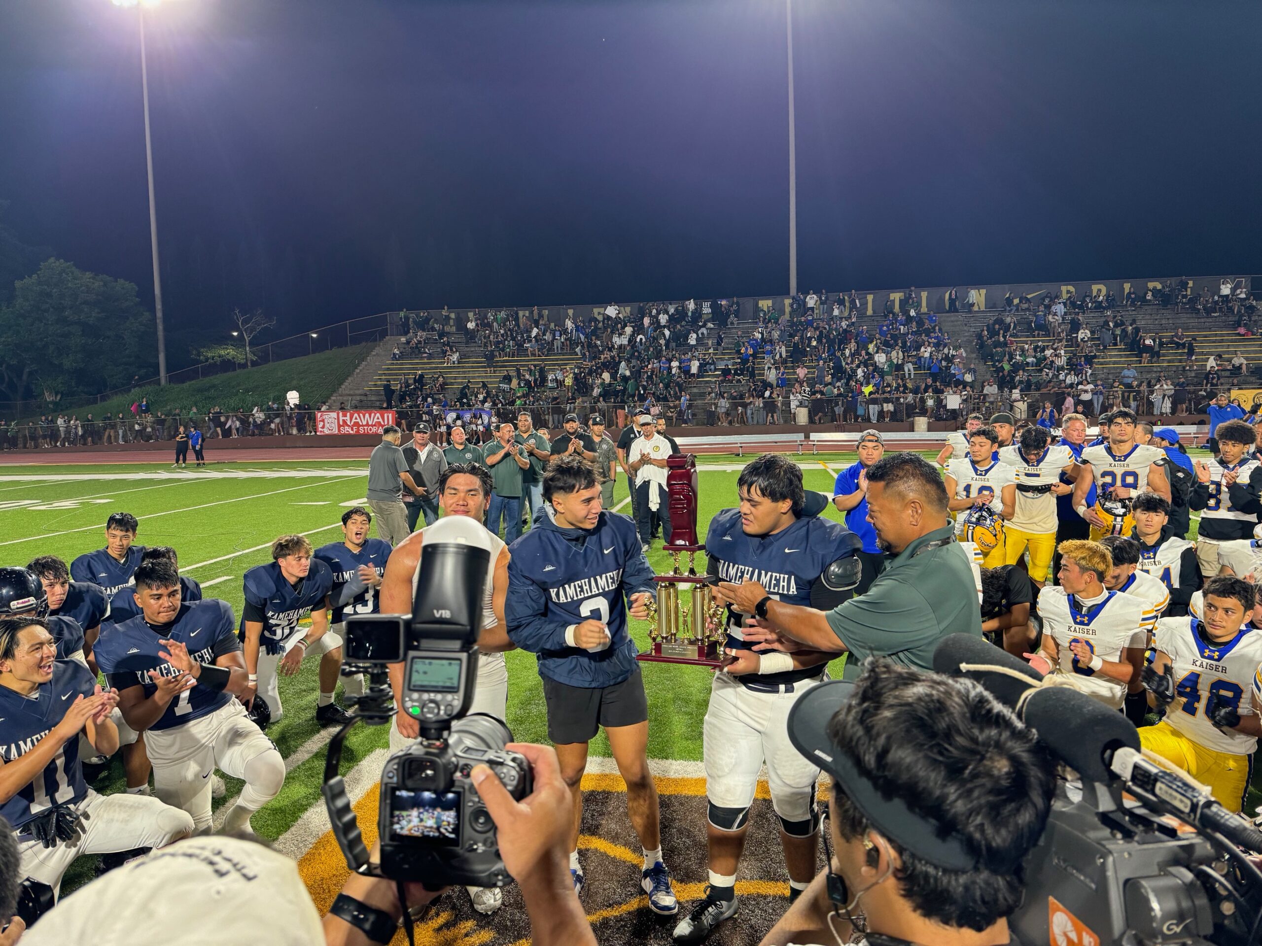 Kamehameha Maui football state champion Ka'onohi Casco (shorts) accepts the state championship trophy at Mililani High School on Saturday along with fellow captaions Ka'iwa Ho (left) and Rusty Ako-Nataniela. HJI / ROB COLLIAS photo