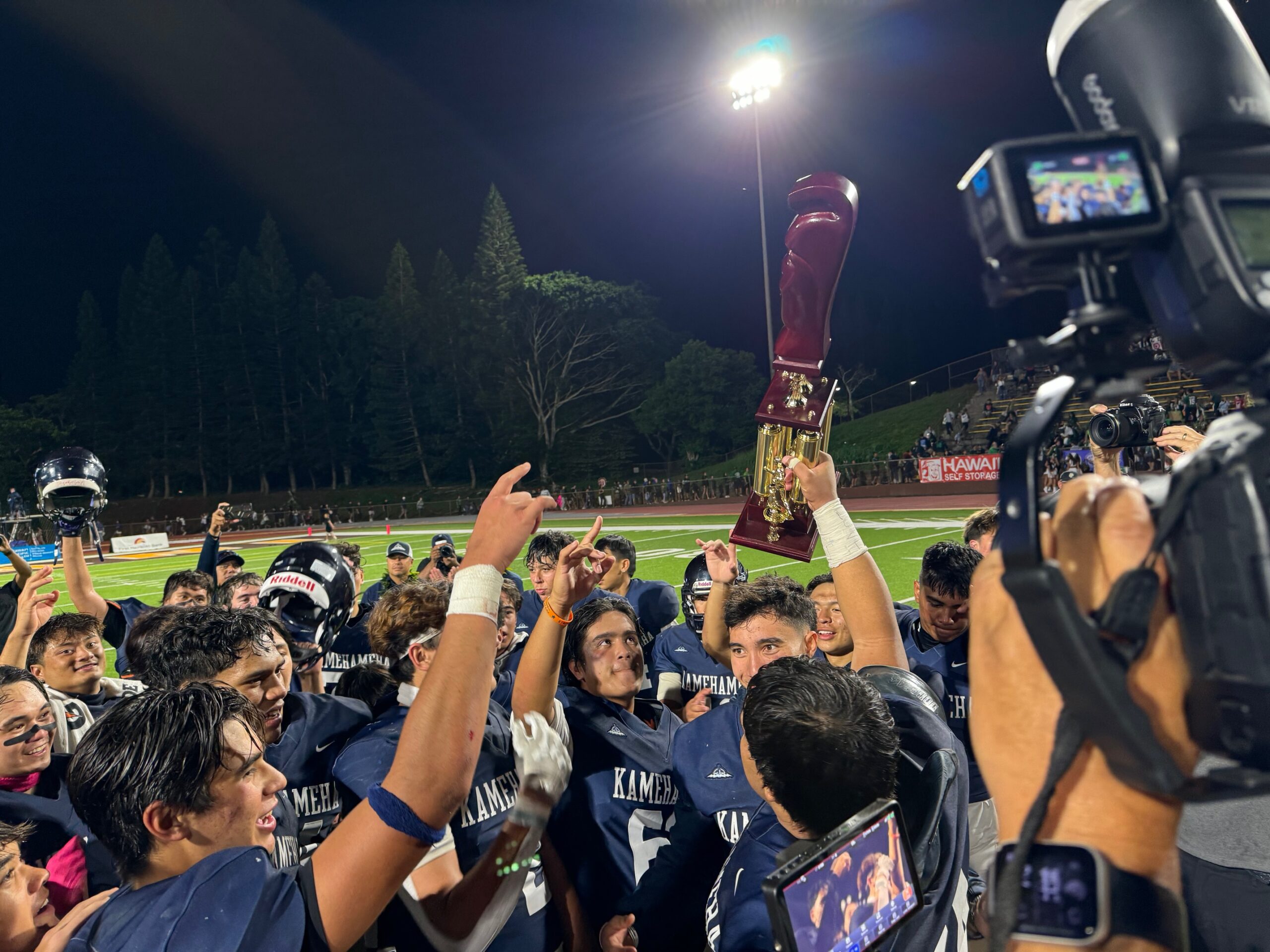 The Kamehameha Schools Maui football team won the Division II state championship with a 37-14 win over Kaiser on Saturday. Team captain Rusty Ako-Nataniela holds up the state championship trophy as his teammates watch. HJI / ROB COLLIAS photo