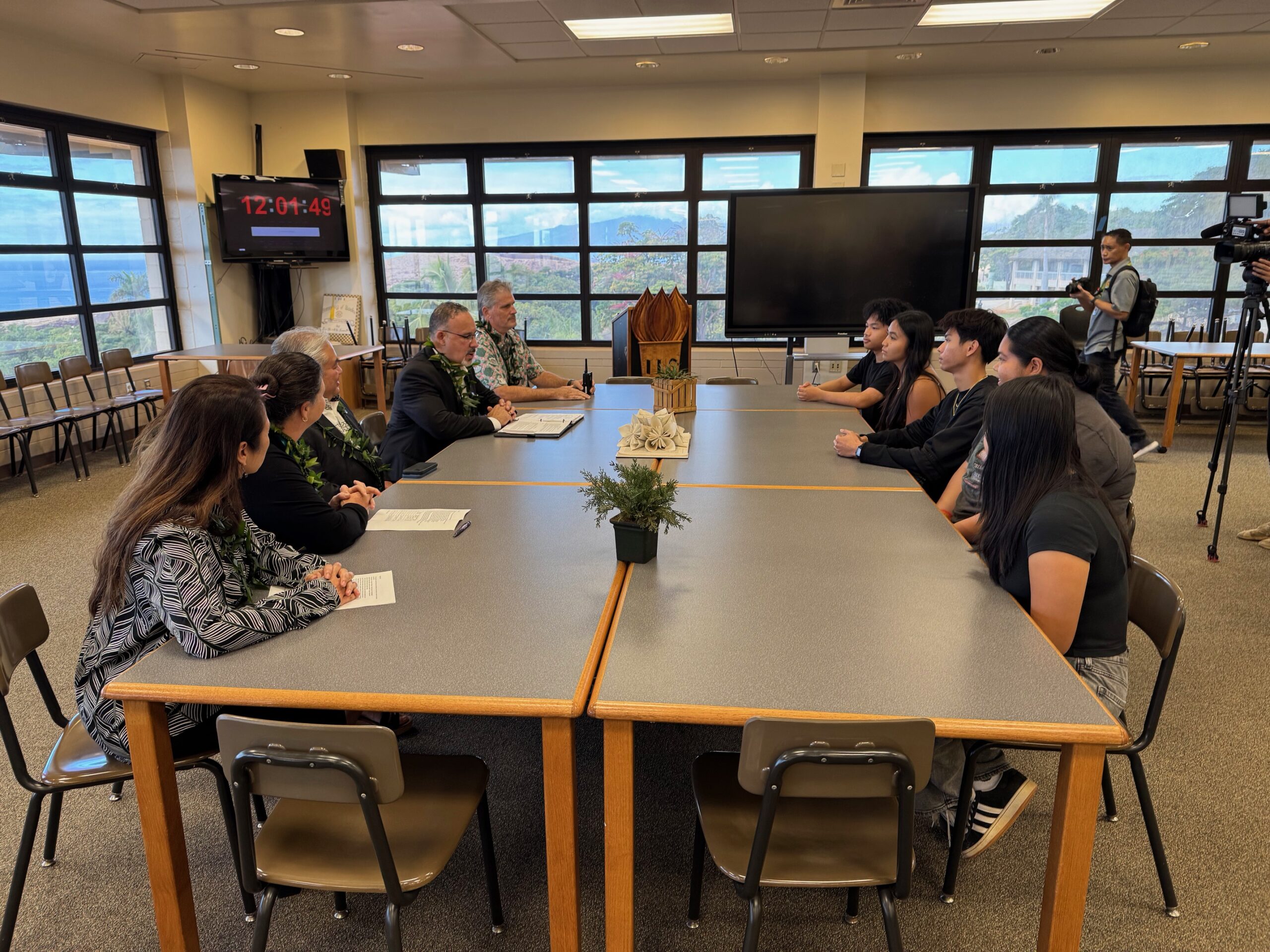 Miguel Cardona, the U.S. Department of Education Secretary (left, in black jacket) meets with Lahainaluna High School students in a roundtable setting on Dec. 6 in the school library. HJI / ROB COLLIAS photo