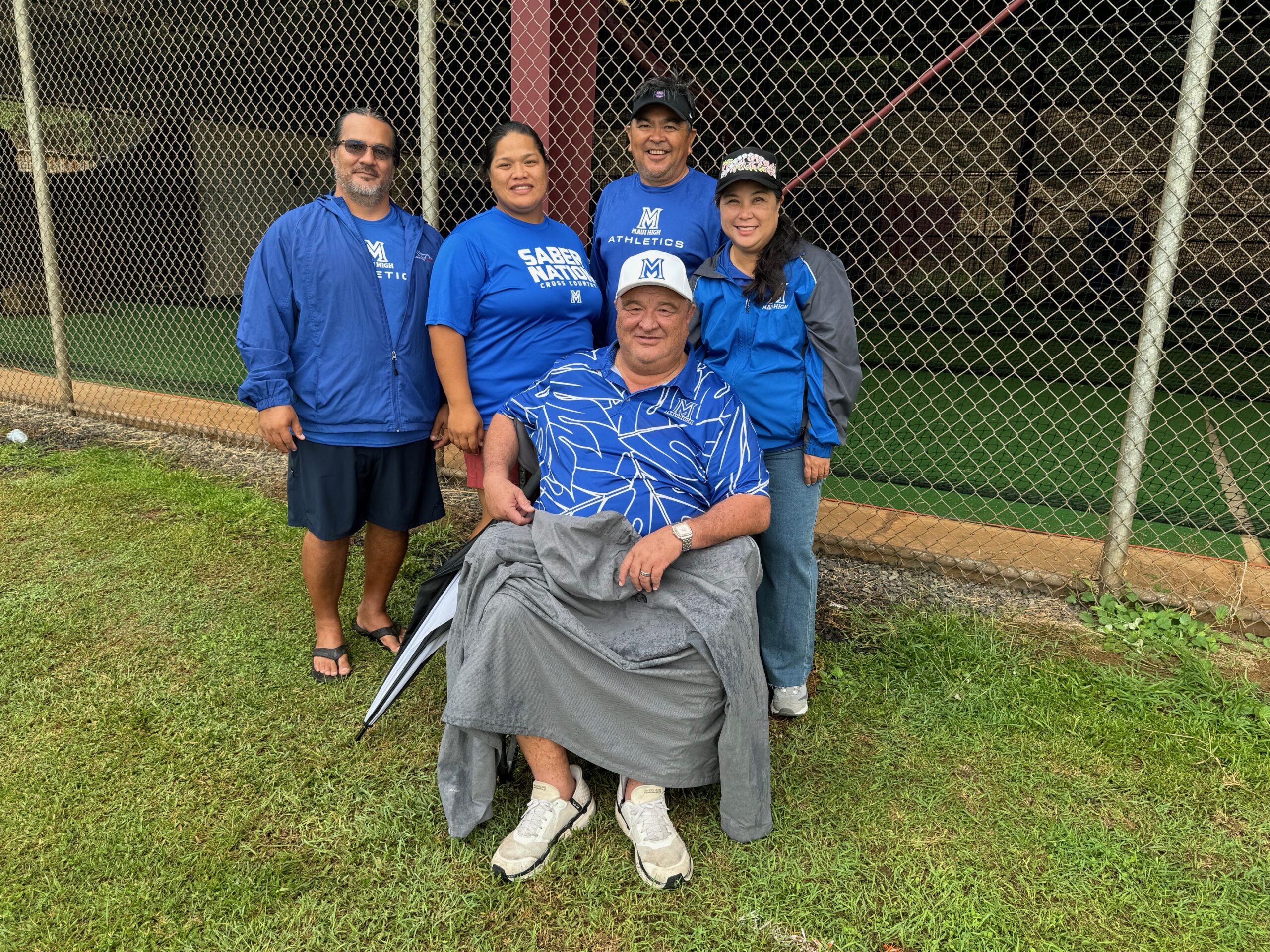 Jamie Yap (stitting), the outgoing Maui High School principal, was surrounded by some of his staff at the Maui Interscholastic League cross country championships at Baldwin in October. From left, Tracy Enos, Leolani Corpuz, Mike Ban and Lianne Dela Cruz stood behind yap at his final MIL meet as a principal. HJI / ROB COLLIAS photo